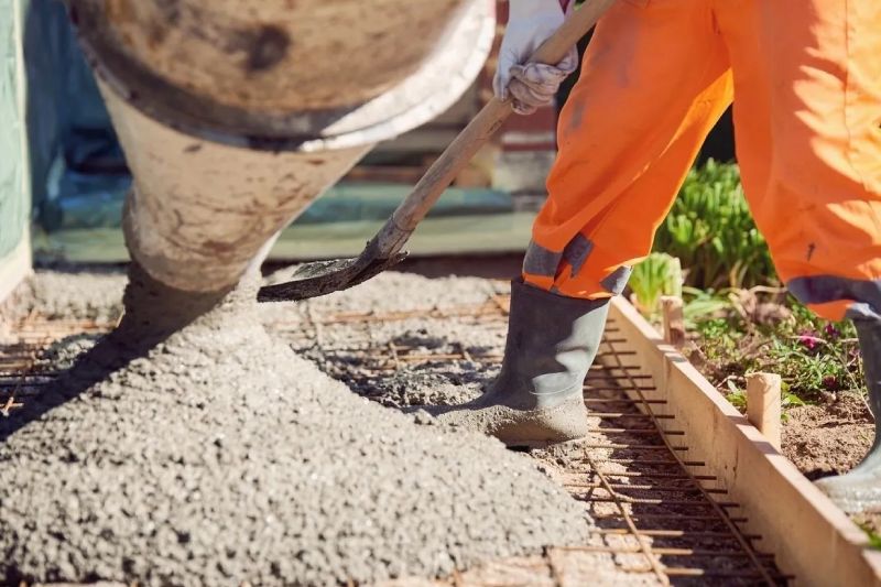 A person in orange pants and boots working on concrete.