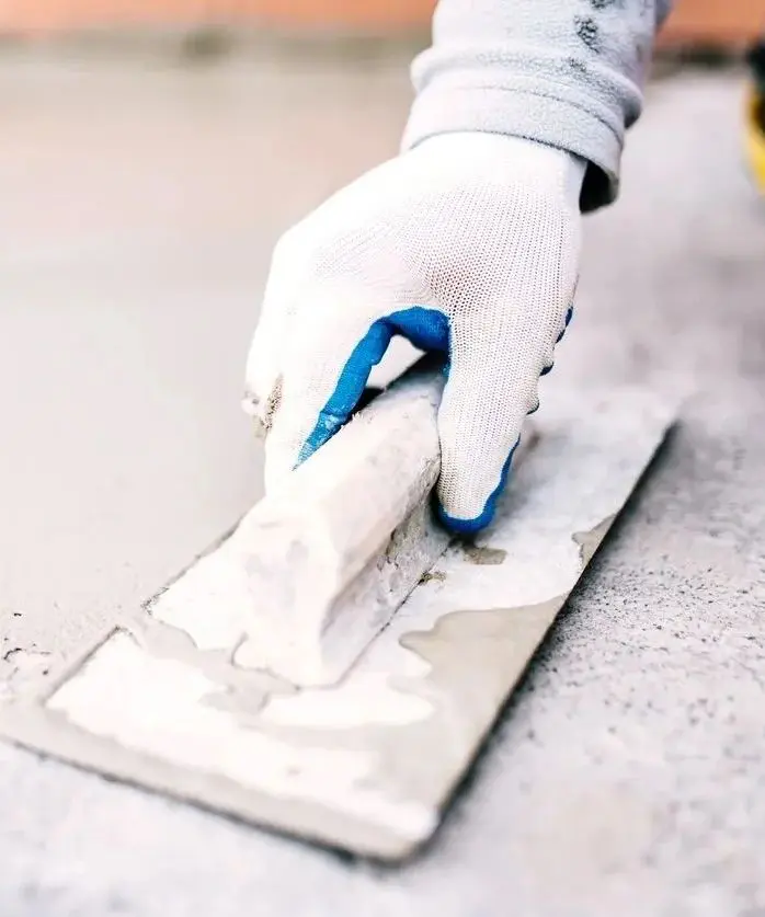 A person wearing gloves and using scissors to cut tile.