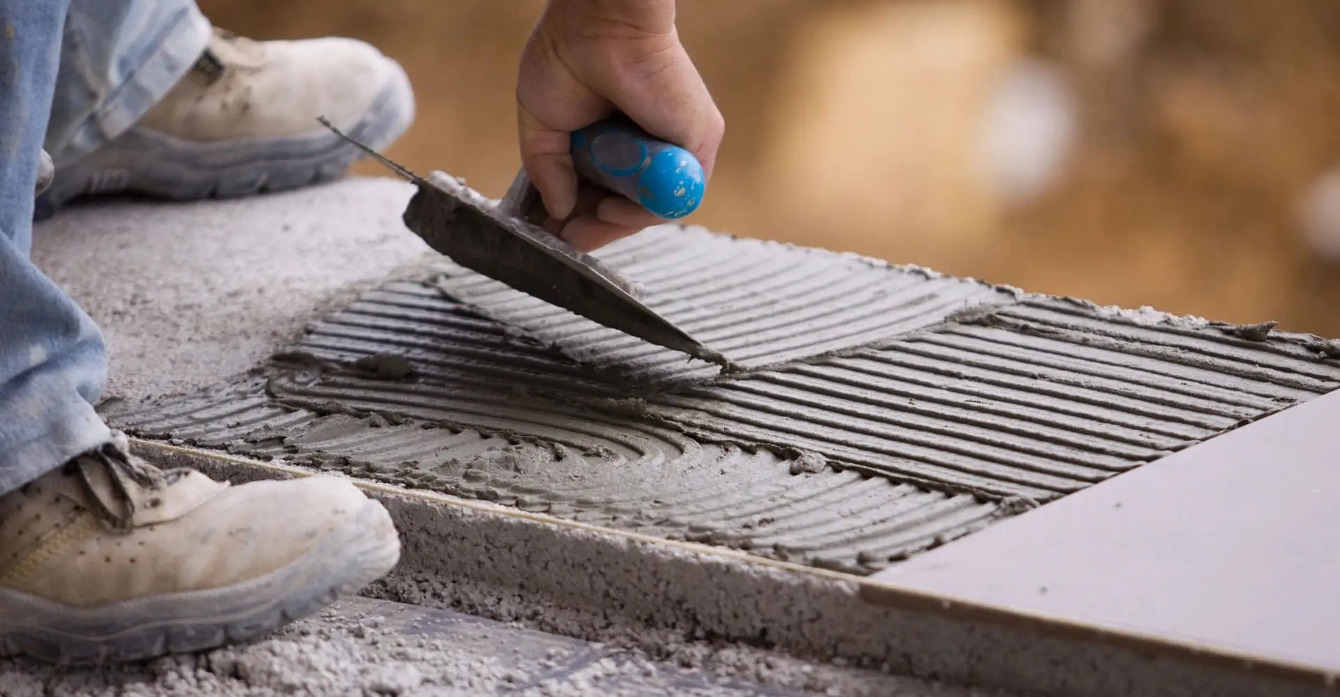 A person using a tile cutter to cut the tiles.